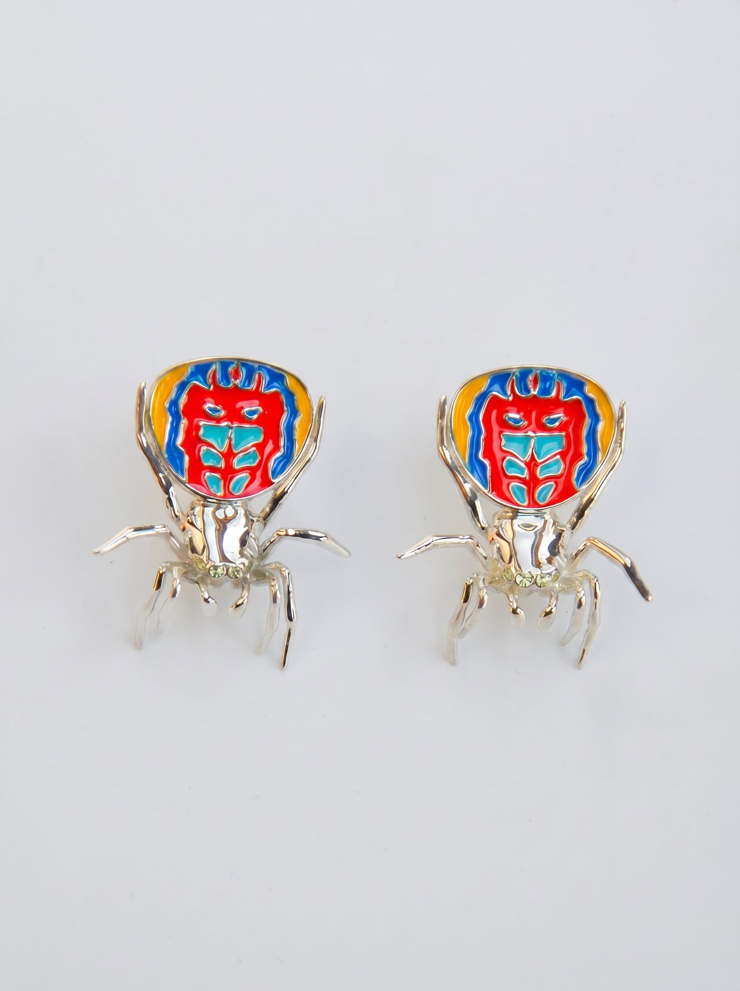 Pair of sterling‑silver peacock spider earrings with vibrant enamel detailing displayed on a white background.