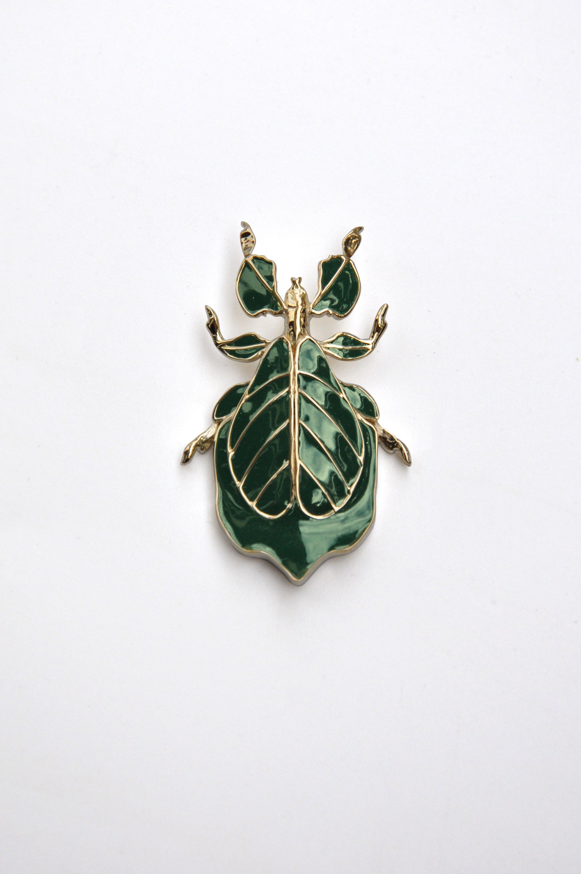 Phylliidae leaf insect pendant in deep green hand-applied enamel with 14k gold-plated detailing, front view showcasing sculptural leaf veins and botanical-inspired design.