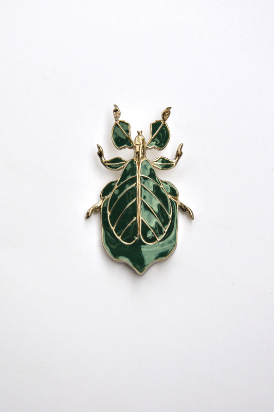 Phylliidae leaf insect pendant in deep green hand-applied enamel with 14k gold-plated detailing, front view showcasing sculptural leaf veins and botanical-inspired design.