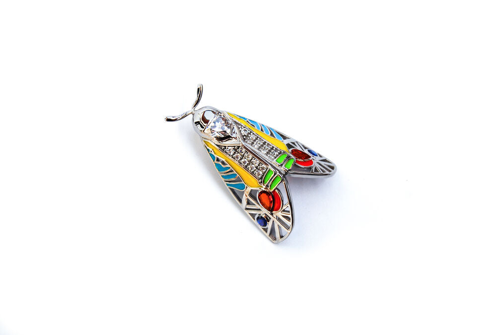 Horizontal view of Picasso Moth pendant with colorful enamel and zirconia stones on white background