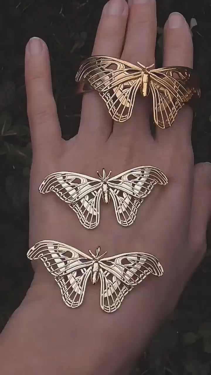 Video still of Atlas Moth Pendant and Bracelet in 14K gold plated finish, held in hand to show movement and polish.