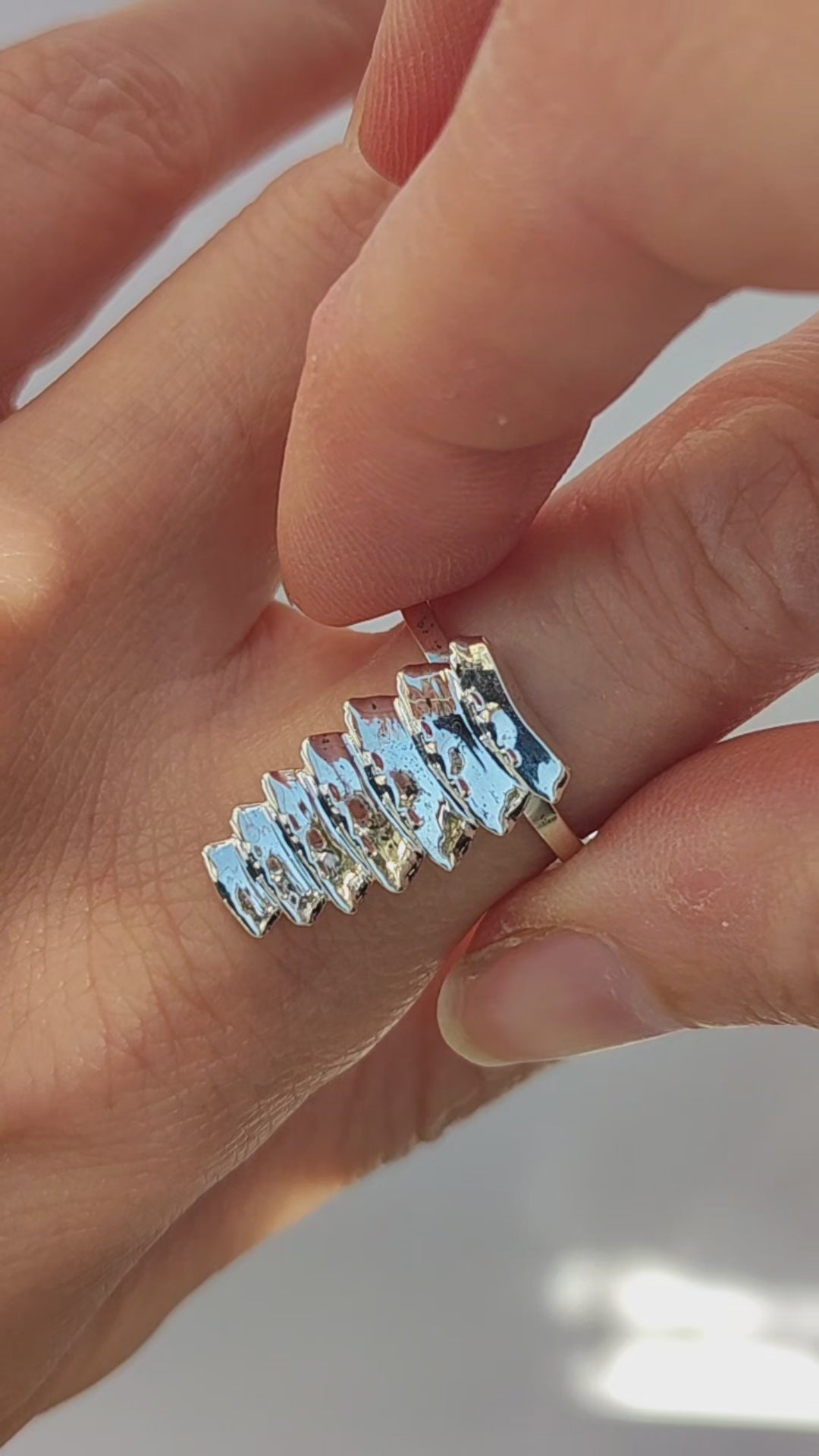 Mixed‑metal trilobite beetle stacking rings—silver, gold, and dark‑toned segments—worn together on one finger to show how the sculptural pieces stack and interlock.