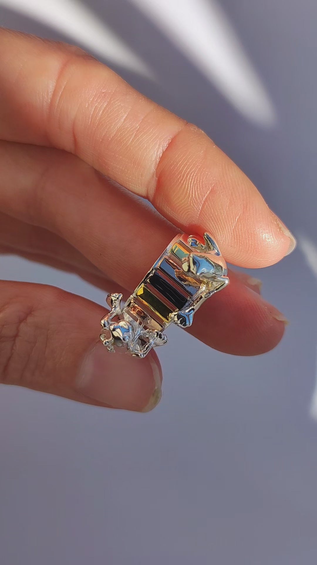 Video showcase of the Frogs on the Rainbow Keys Ring, featuring two sculpted silver frogs performing over miniature rainbow xylophone keys plated in gold, rose gold, black rhodium, and silver.