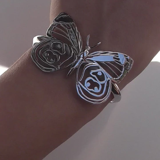 Video still of silver Eighty-eight Butterfly Bracelet on white background, highlighting sculptural wing detail.
