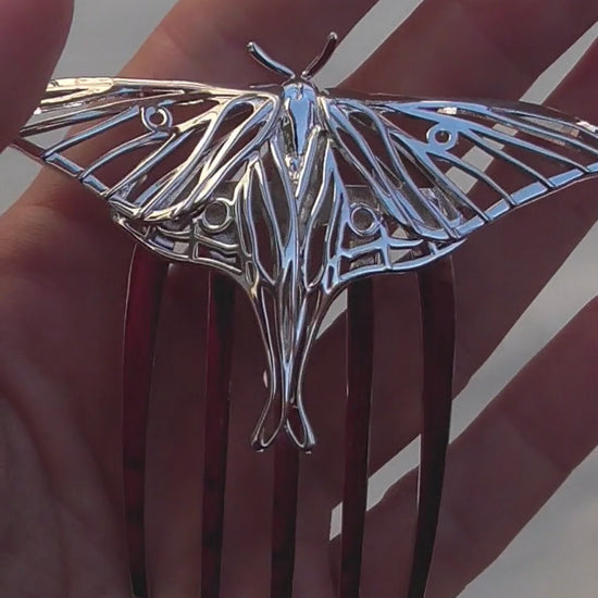 Video showcasing a handcrafted Luna Moth hair comb in rhodium-plated silver finish, displayed on a white background to highlight its intricate wing details and elegant insect-inspired design.