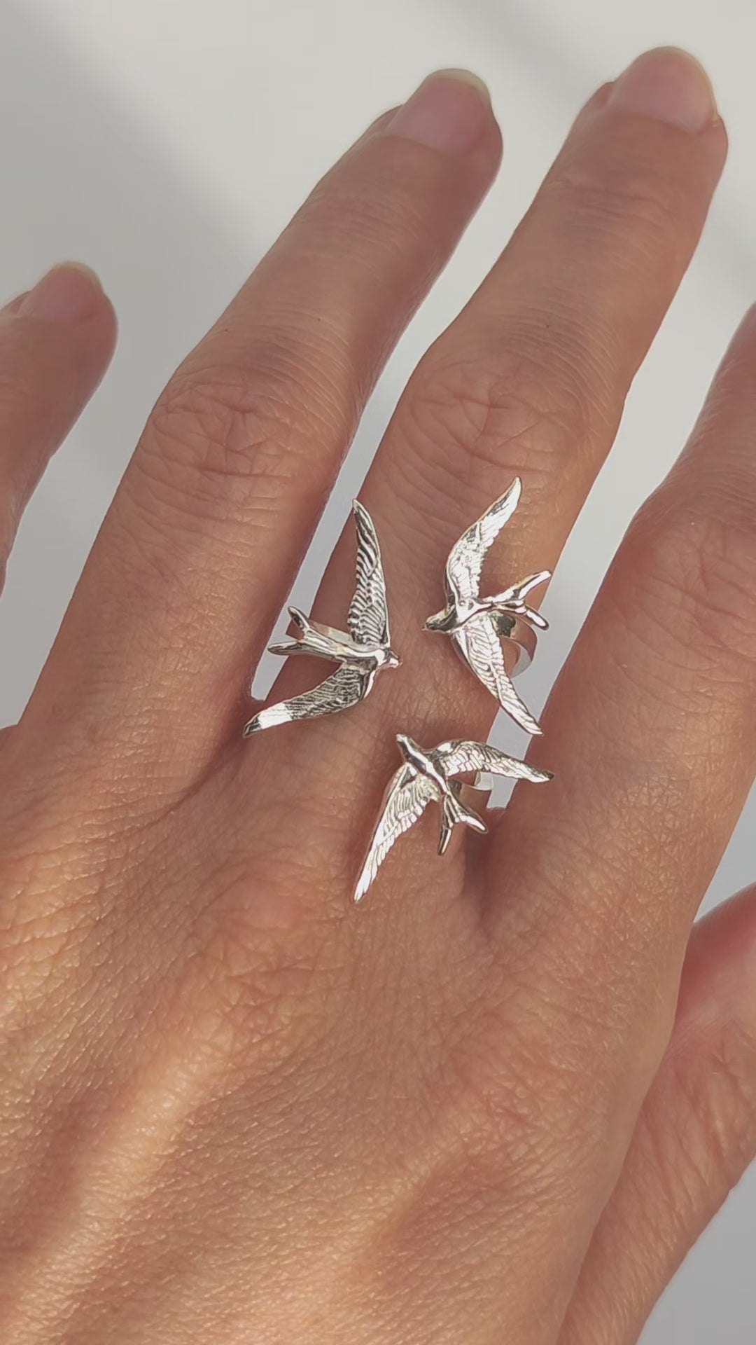 Video preview showing Swallow Gathering Ring worn on hand, capturing light reflections and the fluid motion of the sculpted birds.