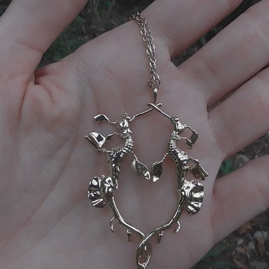 Video still of gold Weedy Sea Dragon Pendant being held, showcasing movement and polished surface.