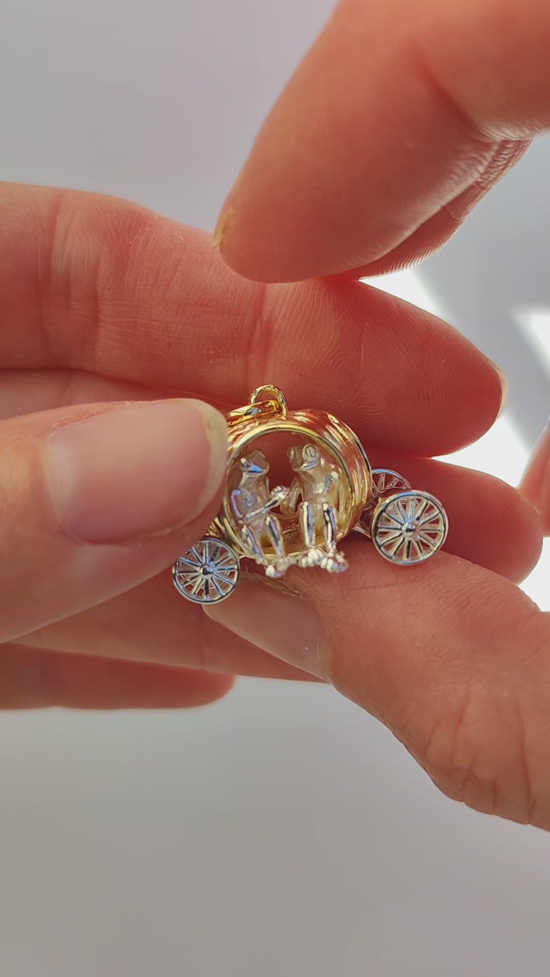 Video showcase of the Frogs in Pumpkin Carriage Pendant, featuring two miniature frogs seated hand‑in‑hand inside a sculpted pumpkin carriage with freely spinning wheels and curling root details.