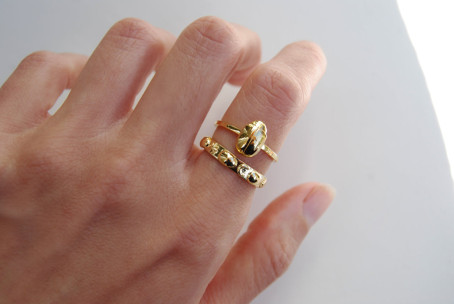 Celestial scarab stacking rings worn on finger in 14K gold plated finish, showcasing symbolic insect jewelry with cosmic detail.