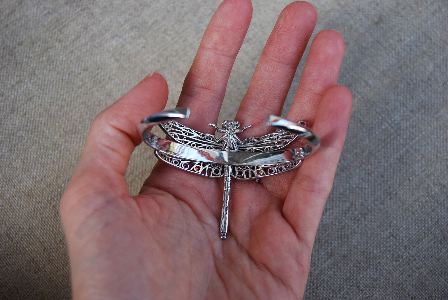 Silver dragonfly accessory displayed on the back, highlighting delicate wing details and metallic shine.