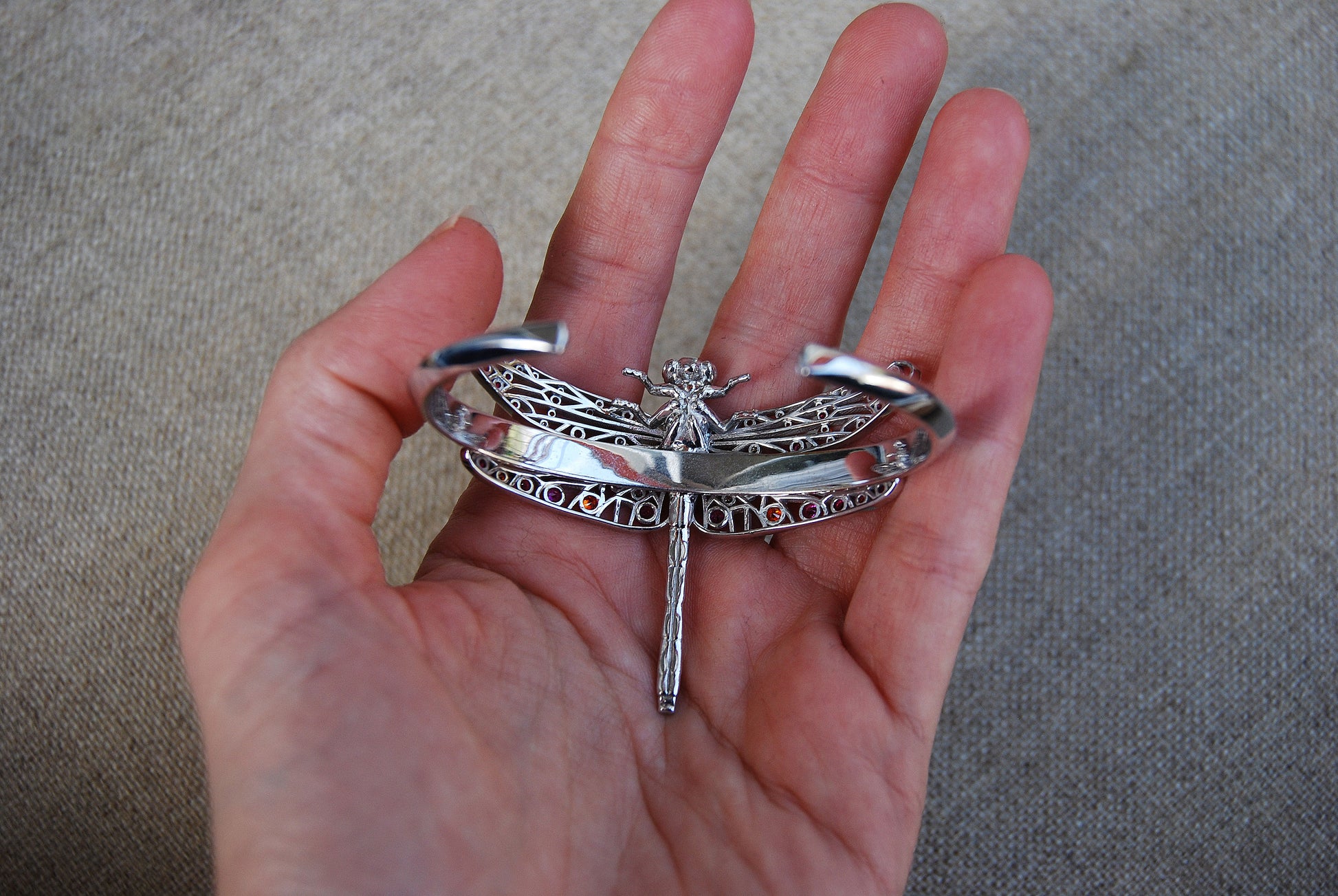 Silver dragonfly accessory displayed on the back, highlighting delicate wing details and metallic shine.