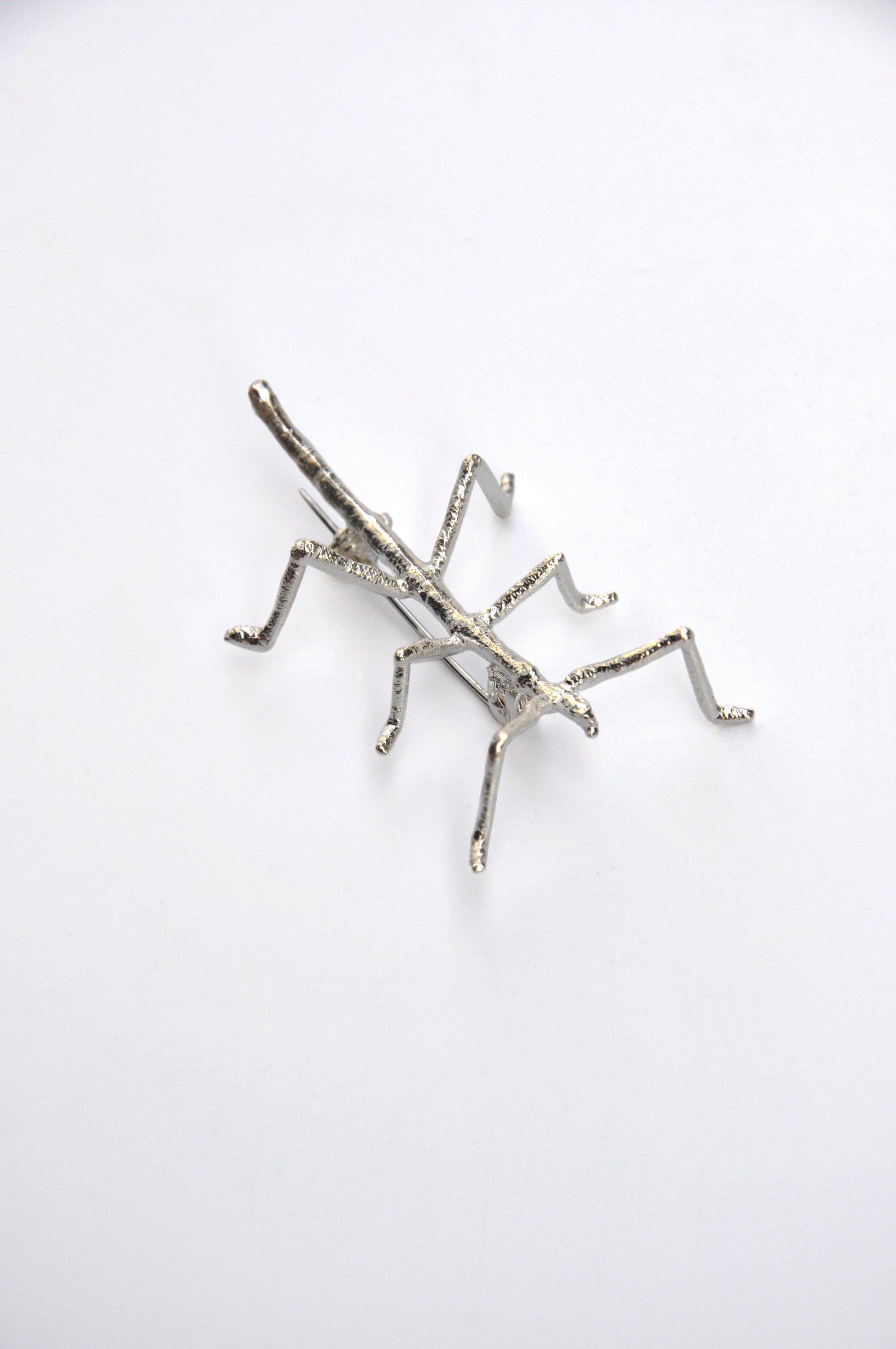 Angled view of the silver stick insect brooch on white background, highlighting the delicate craftsmanship.