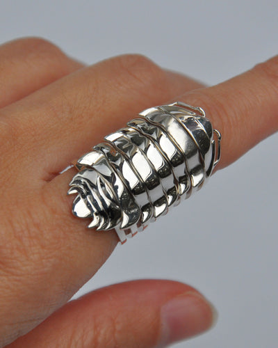 Hand wearing stacked silver isopod rings inspired by segmented armor and fossil design.