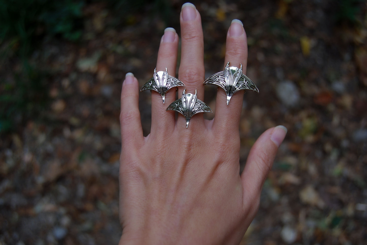 Hand adorned with sterling silver manta ray rings, featuring handcrafted sea creature jewelry.