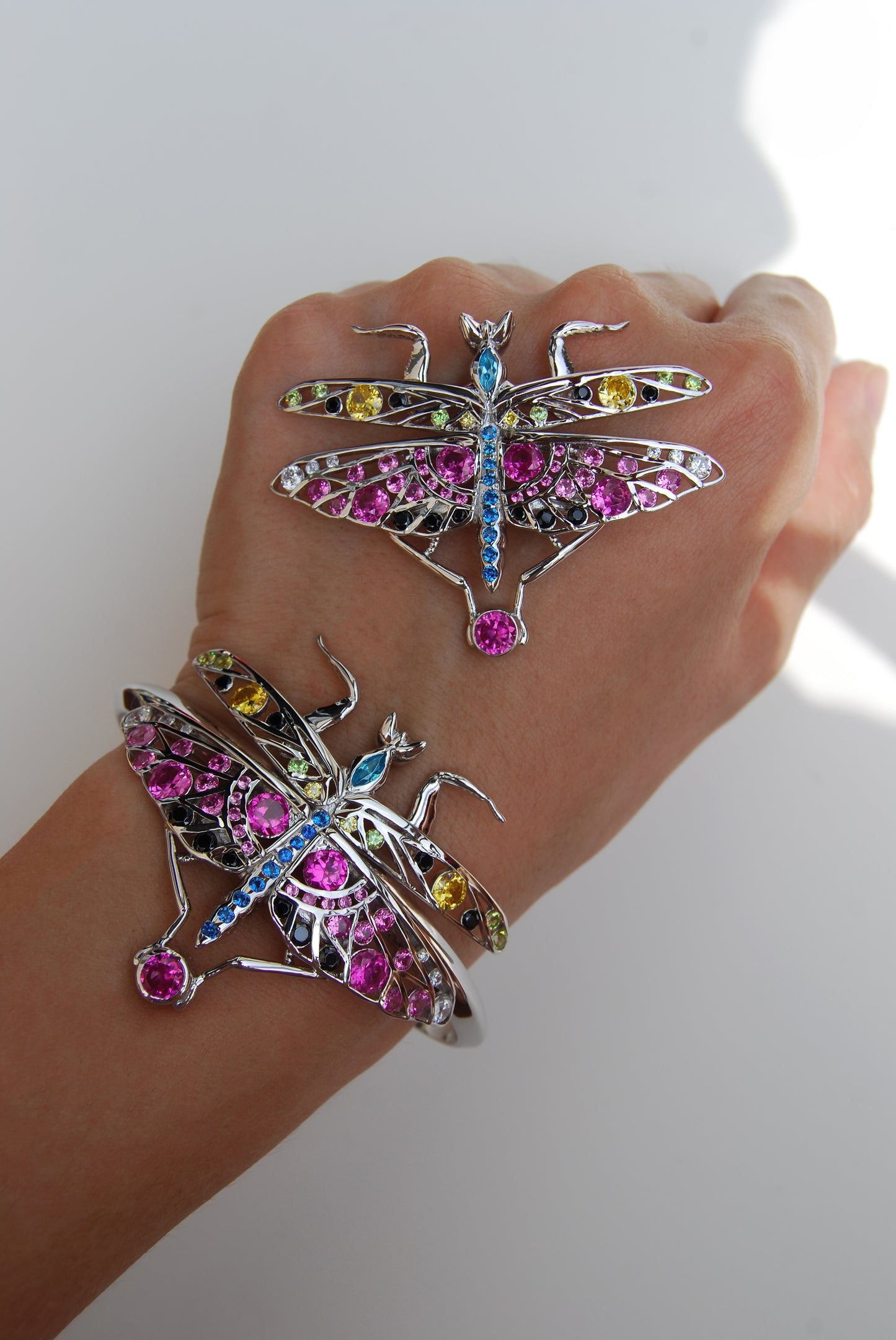 Silver praying mantis bracelet and pendant displayed on hand against white background, highlighting detailed insect-inspired design and polished metal finish