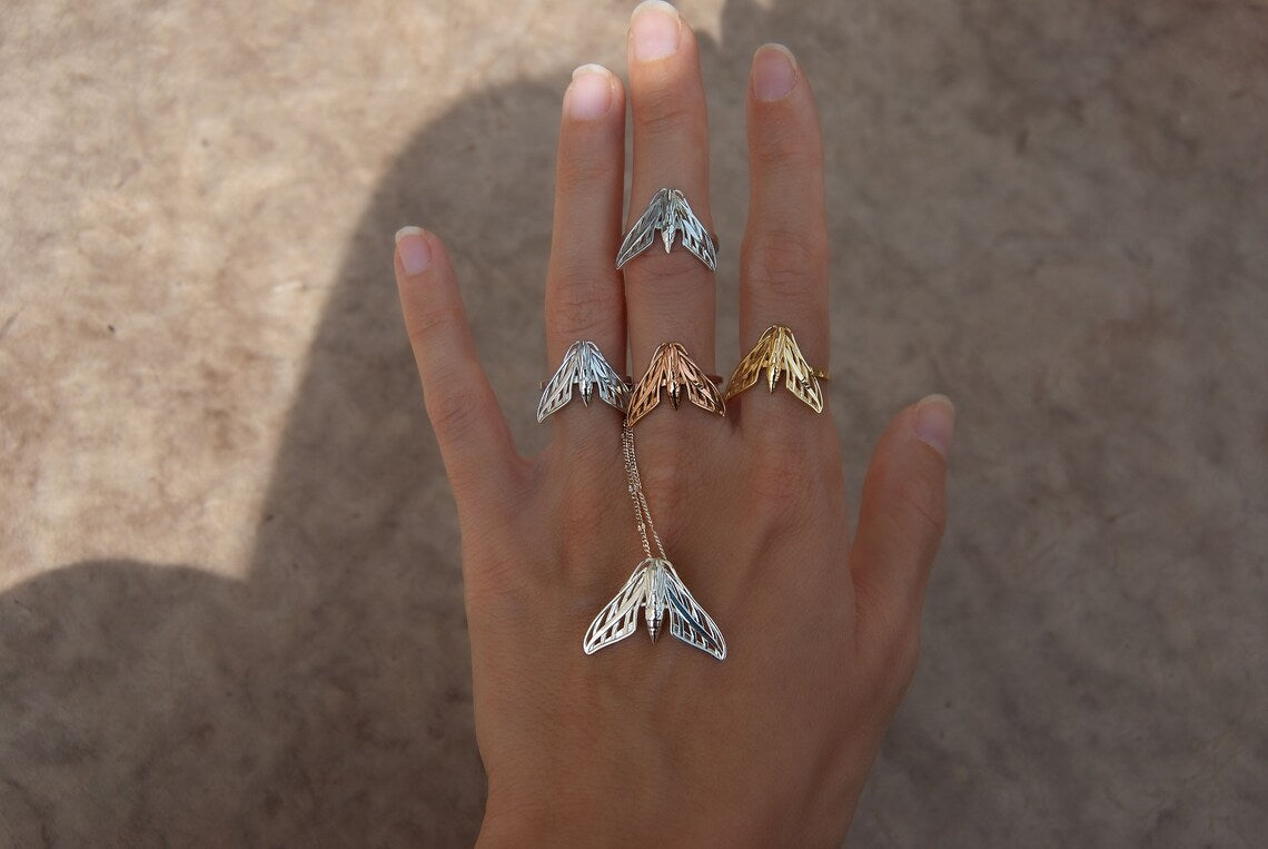 Alternate view of full sphinx moth ring collection in silver and gold on hand, styled as celestial statement jewelry.
