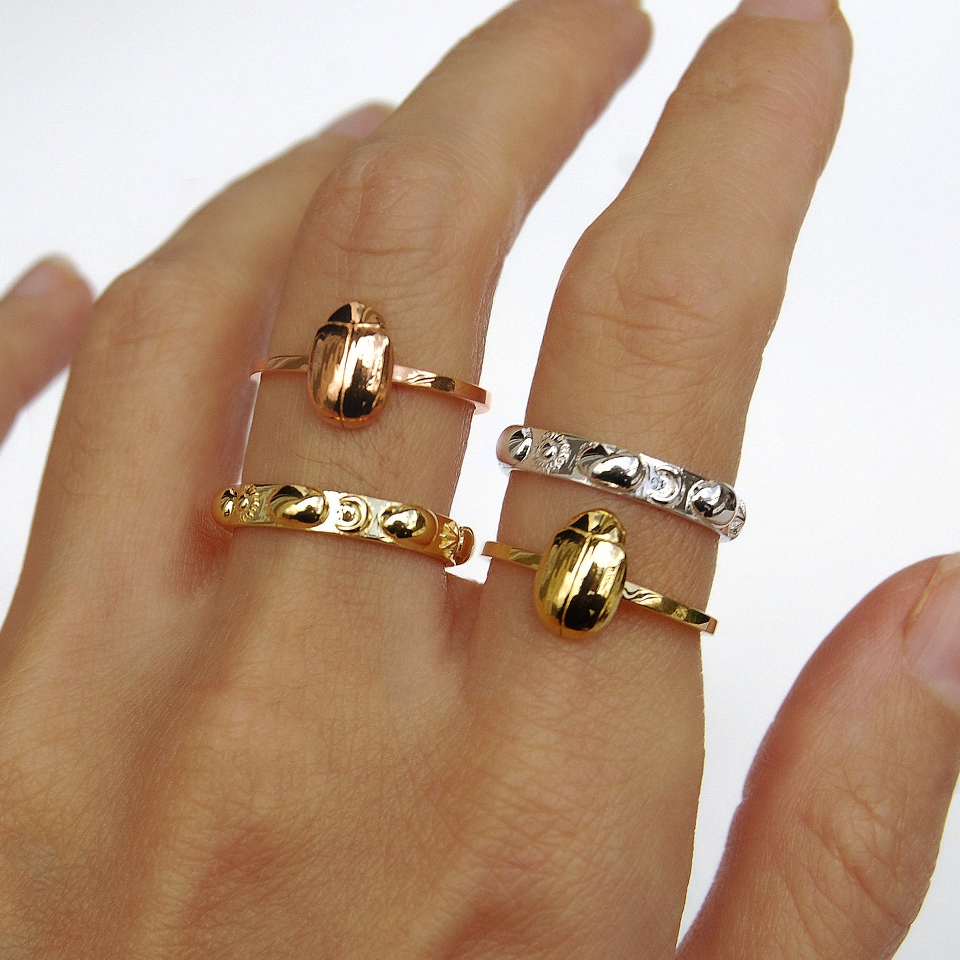 Trio of celestial scarab stacking rings in gold, rose gold, and silver, emphasizing handcrafted bug jewelry in varied finishes.