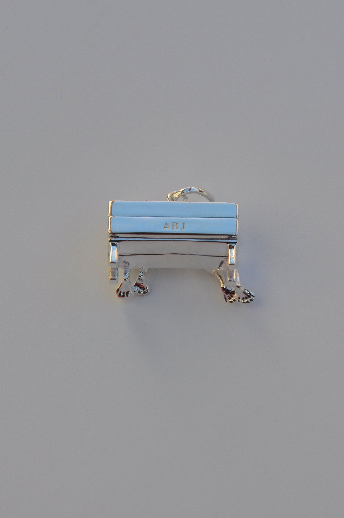 Miniature bench charm engraved with ARJ, designed as part of the Stargazer Frogs collectible pendant series.