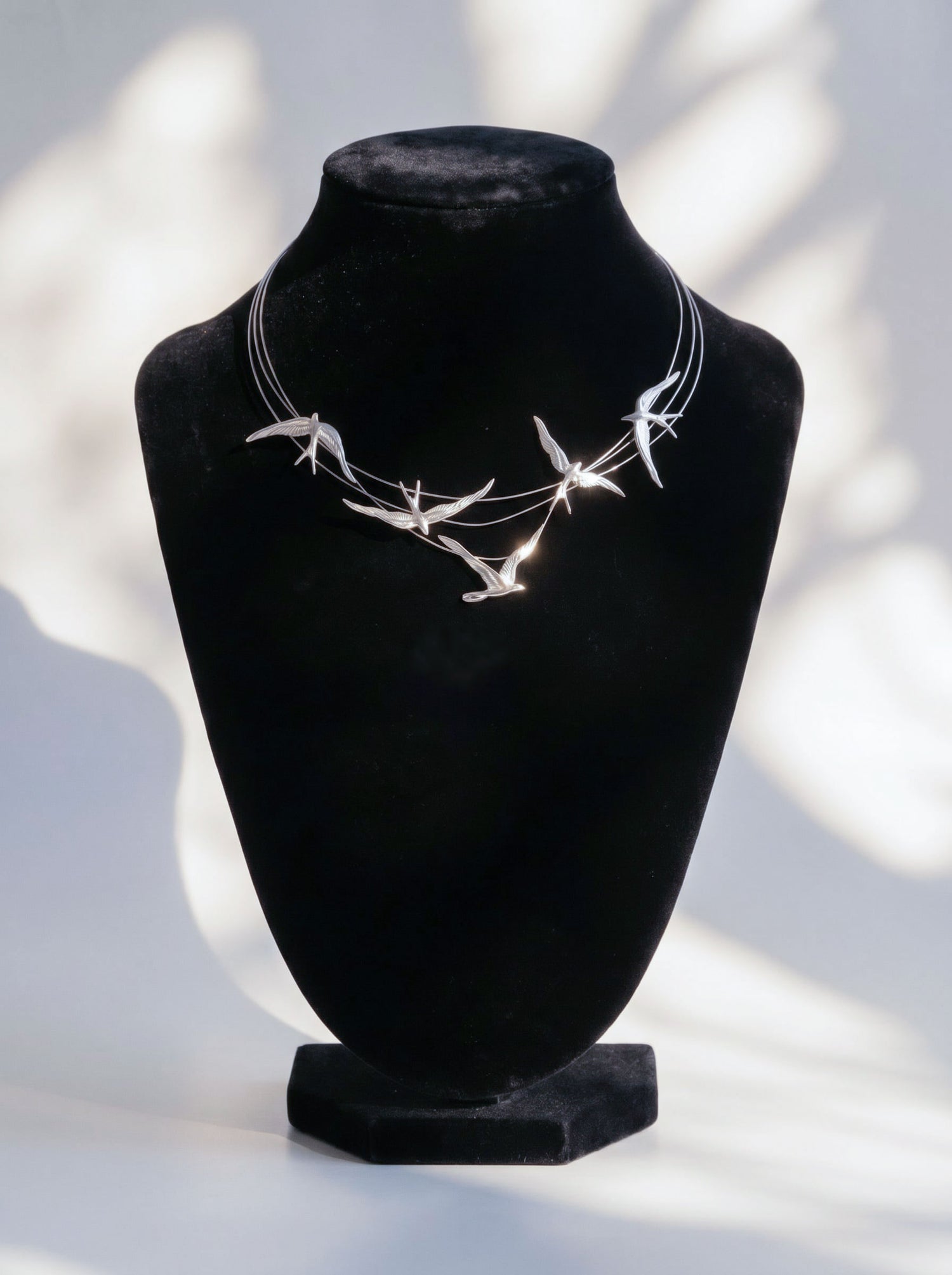 Swallow Arch Necklace in sterling silver displayed on black bust, showing sculptural birds forming a graceful arc in flight.