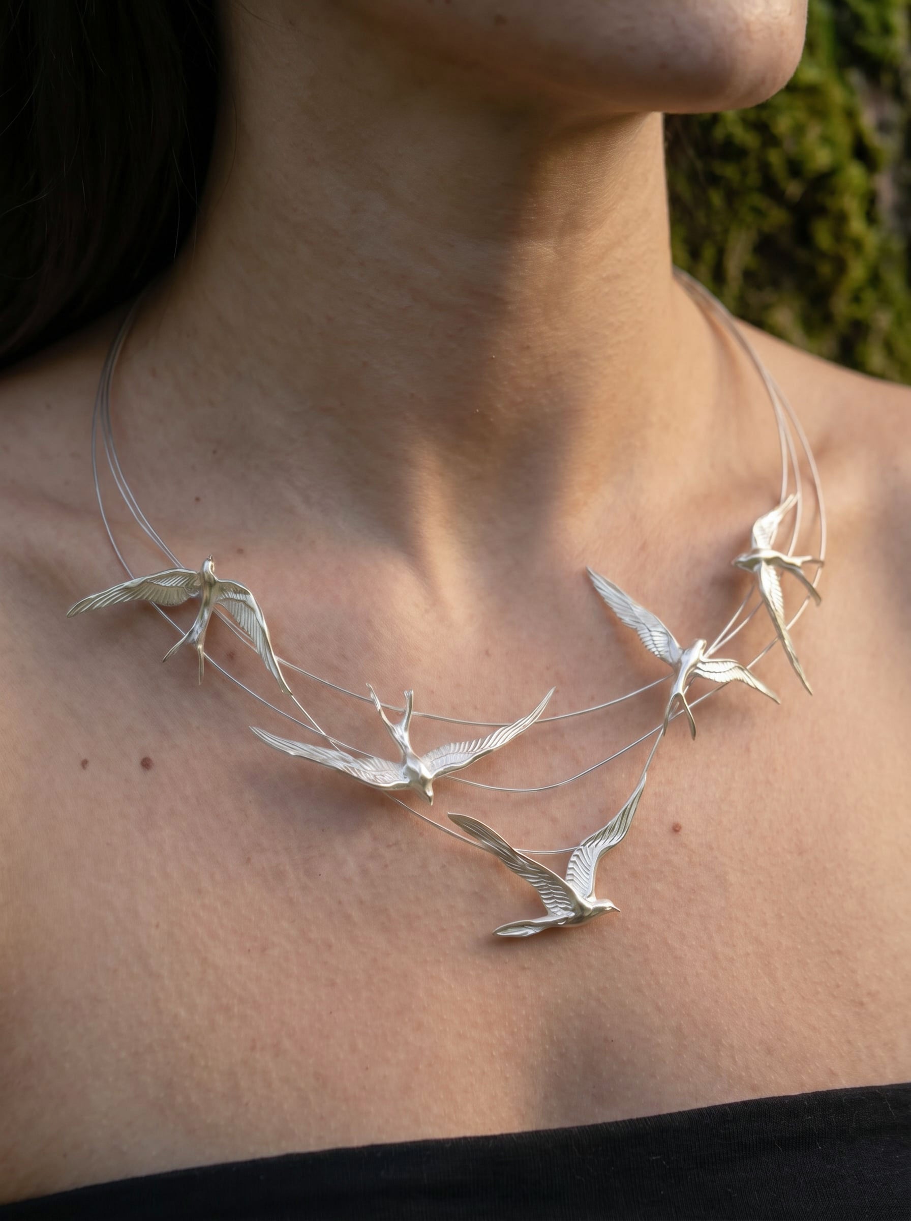 Swallow Arch Necklace worn close‑up, capturing polished silver texture and fluid Art Nouveau‑inspired movement.