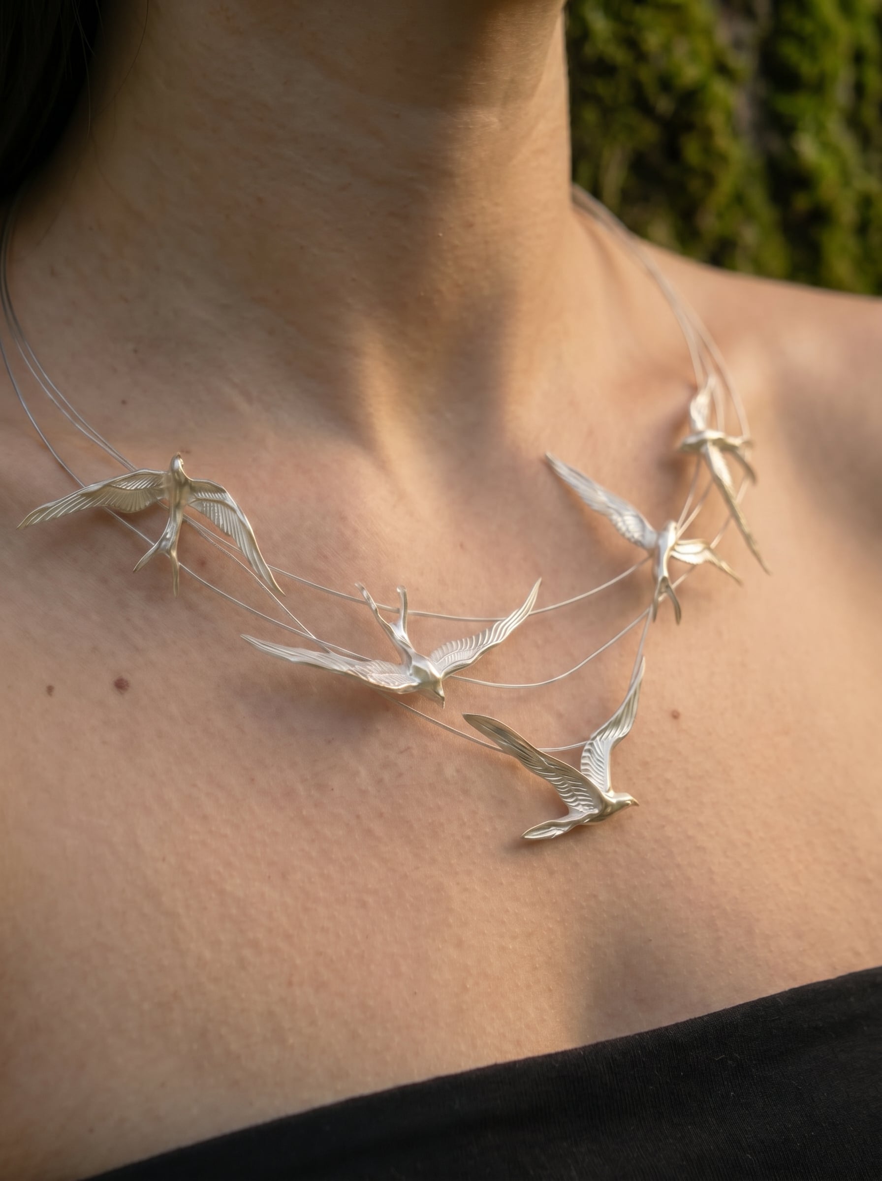 Swallow Arch Necklace worn on neck, showing elegant curvature and balanced arrangement of silver birds in flight.