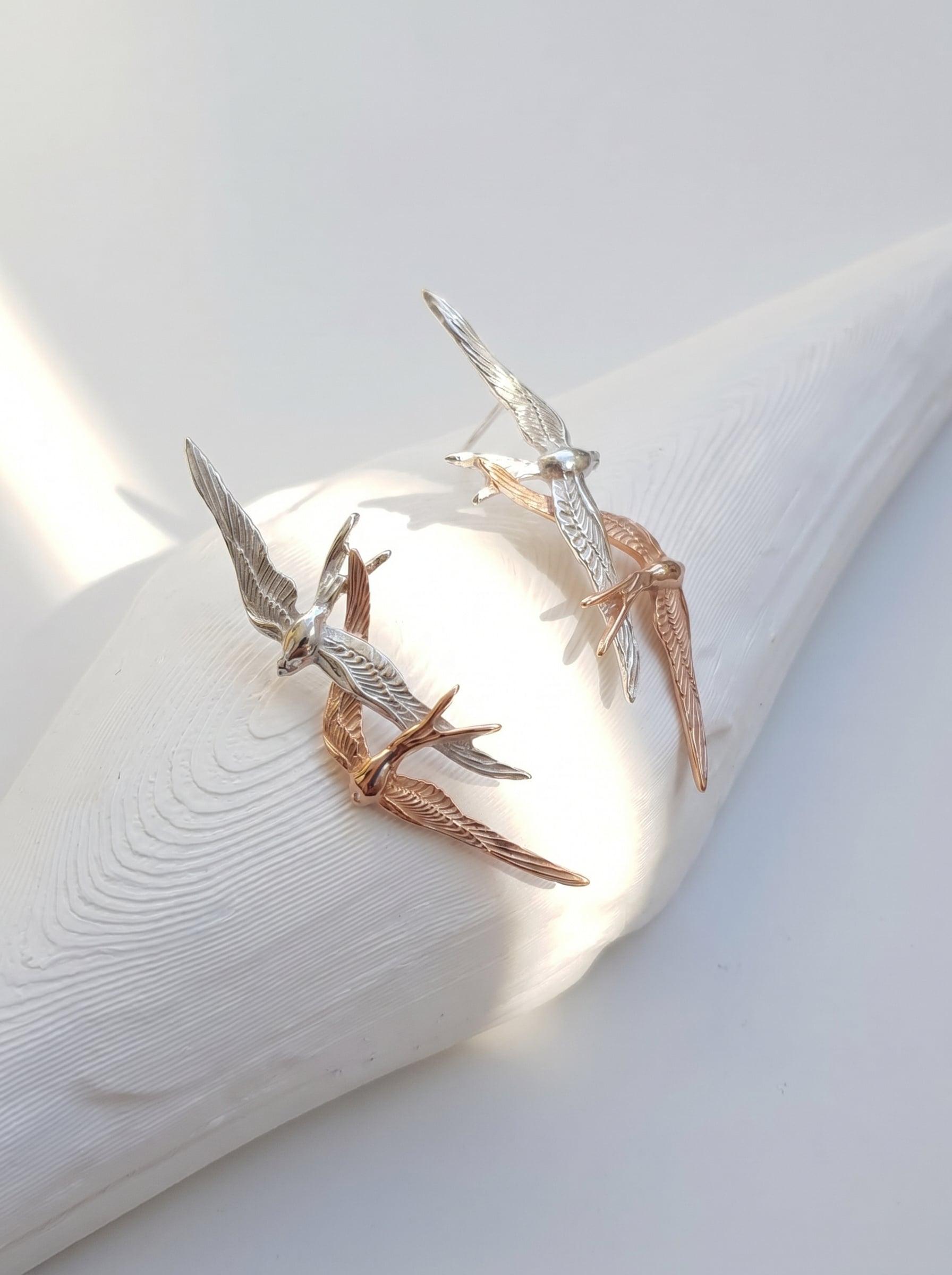 Swallow Flight Stud Earrings photographed at an angle, revealing fine feather engravings and warm rose‑gold highlights.