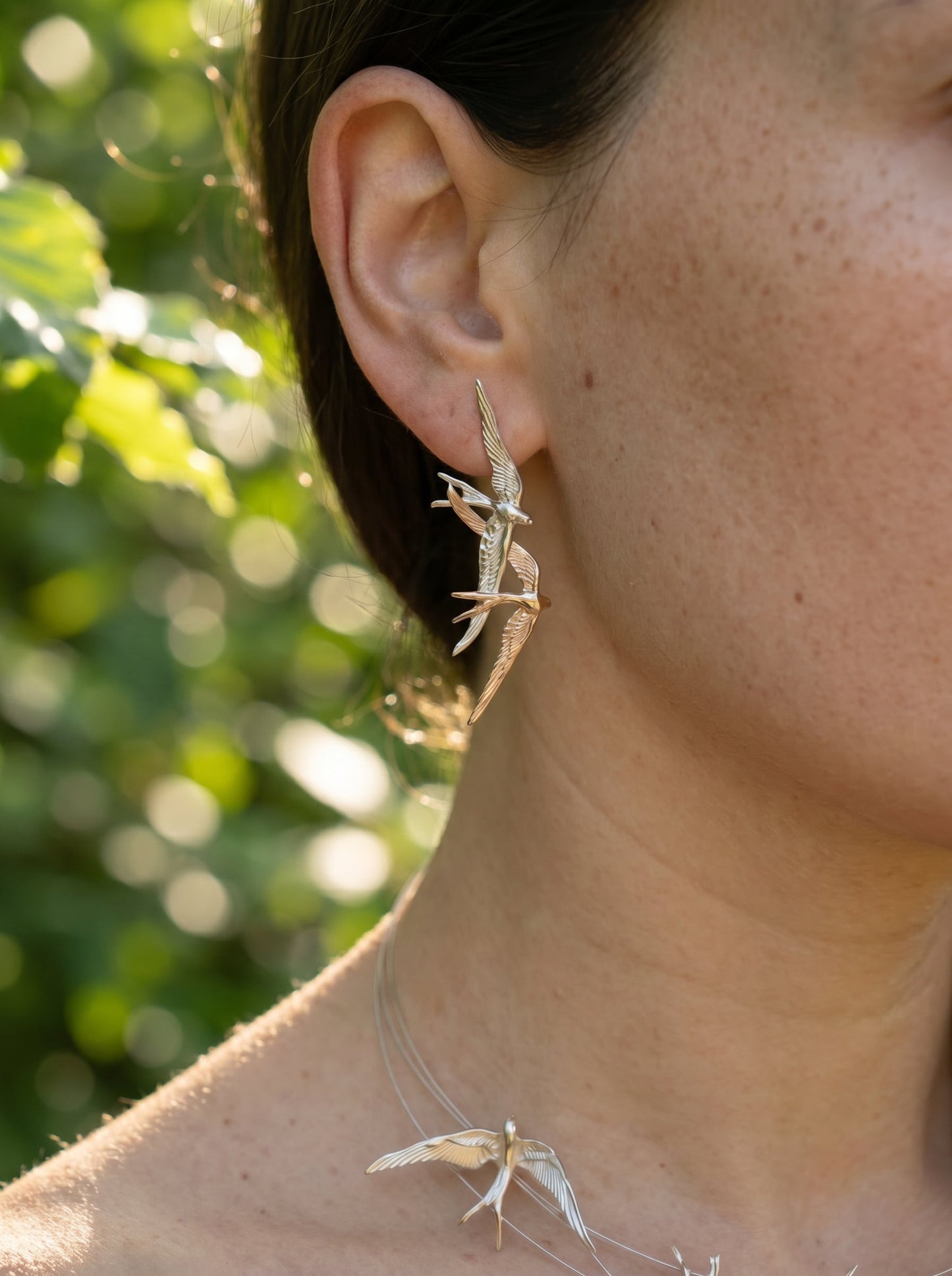 Swallow Flight Stud Earrings worn on ear in soft outdoor light, highlighting sculptural movement and romantic asymmetry.