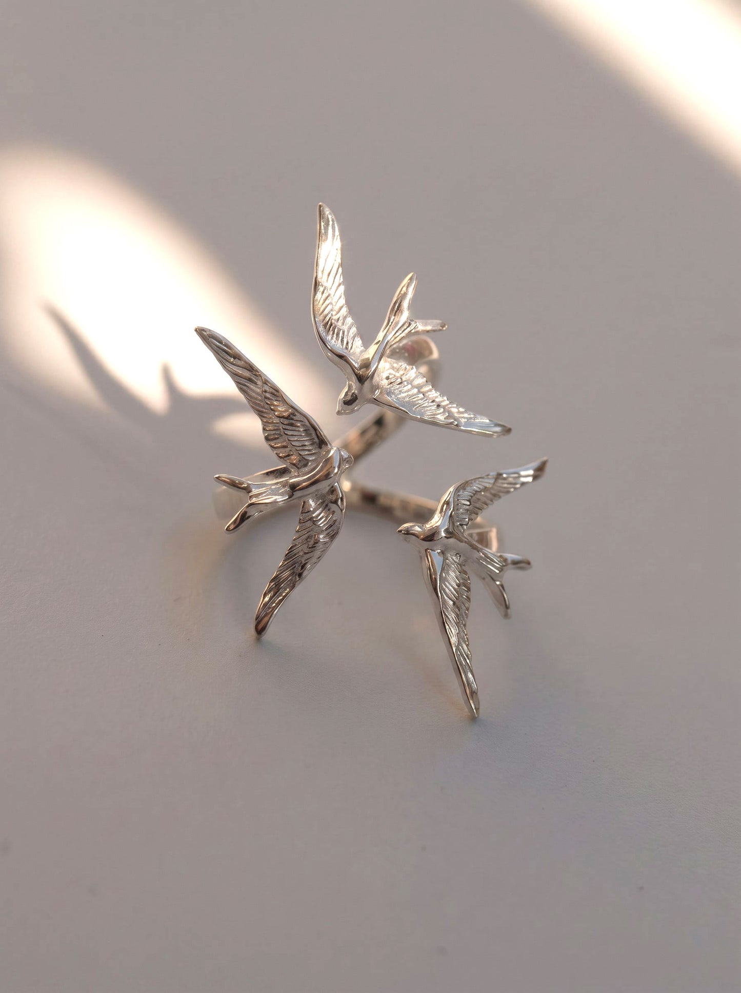 Swallow Gathering Ring photographed with soft shadows, emphasizing sculptural geometry and Art Nouveau inspiration.