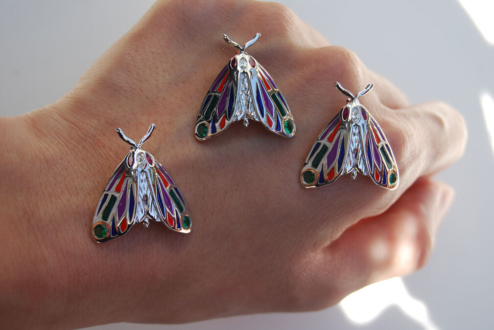 Another view of a collection of Tiger Moth pendants held on hand
