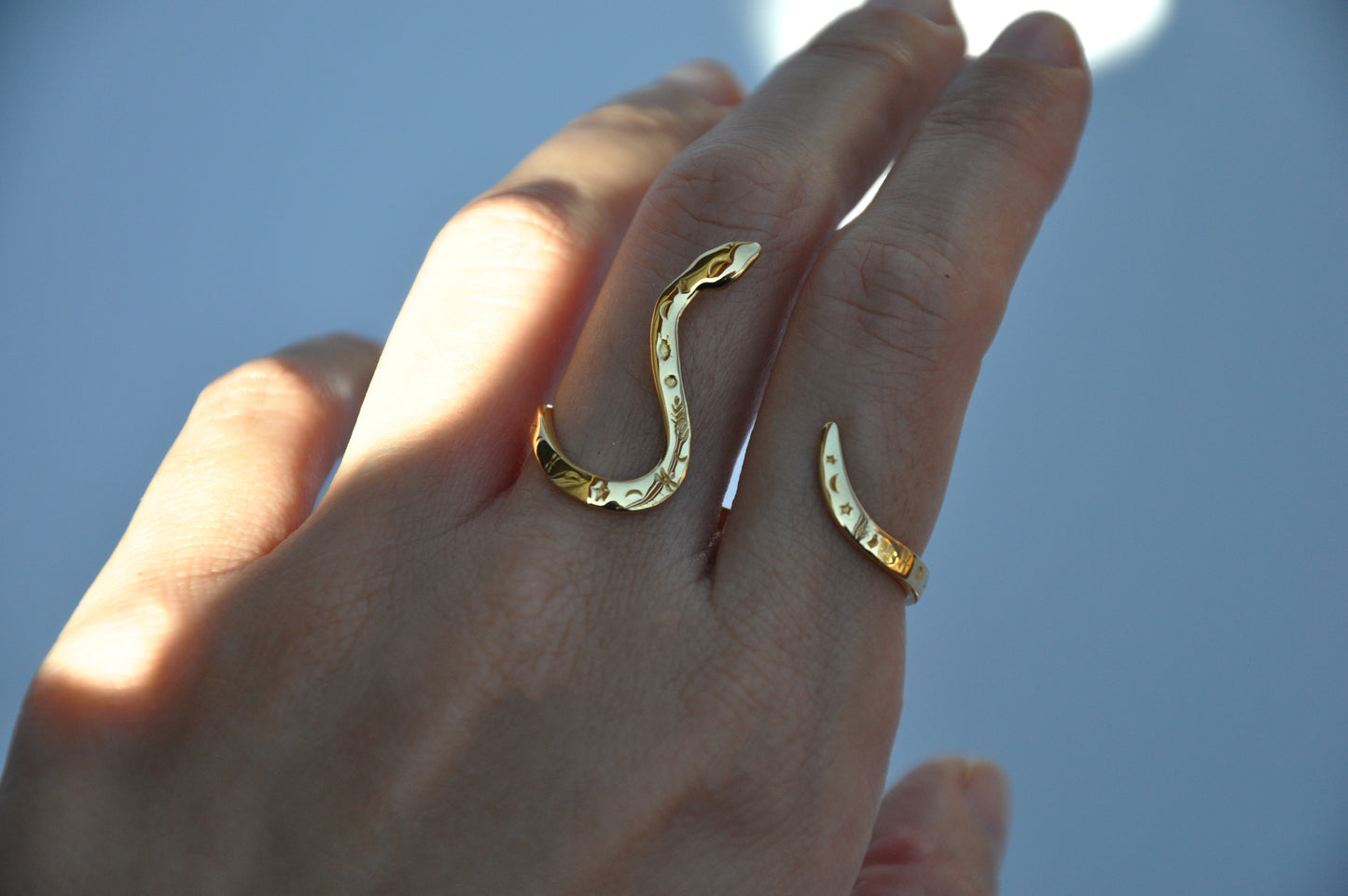 Model wearing two-finger celestial snake ring, styled as mystical statement jewelry with cosmic symbolism.
