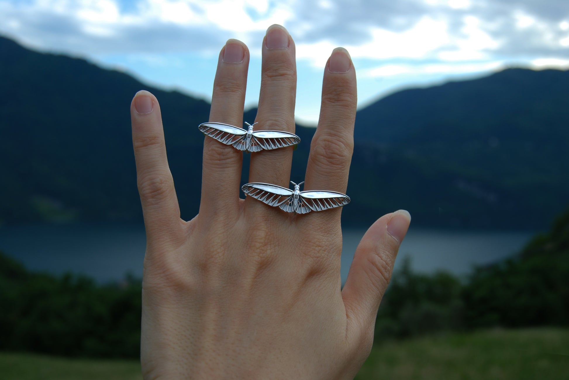 Two sterling silver butterfly rings styled across fingers, bold statement insect jewelry.