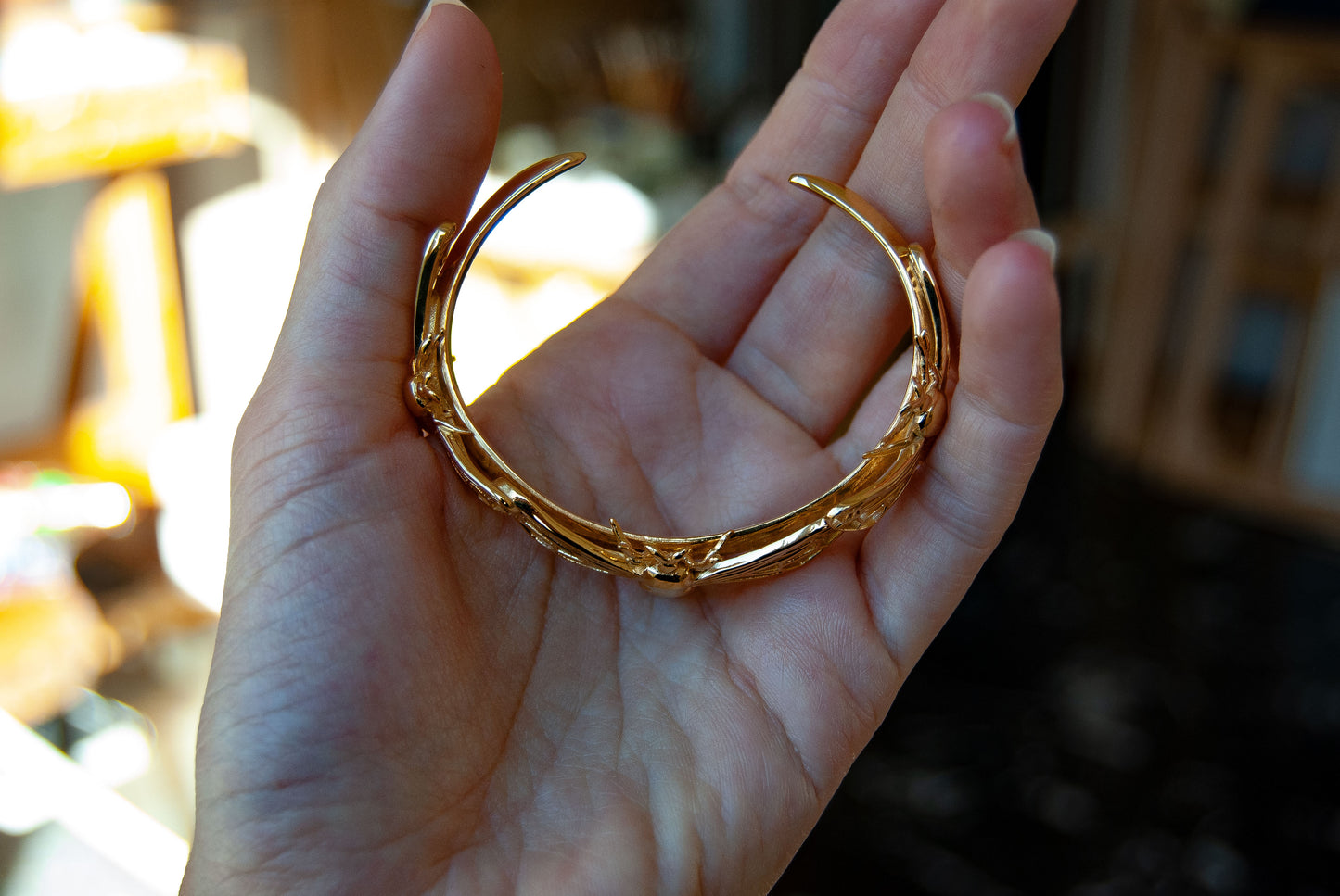 Top view of gold bee cuff bracelet held in hand, capturing detailed symmetry.