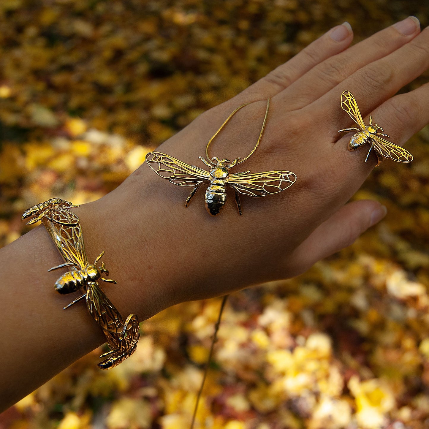 Bee pendant and matching rings worn on hand, top-down view