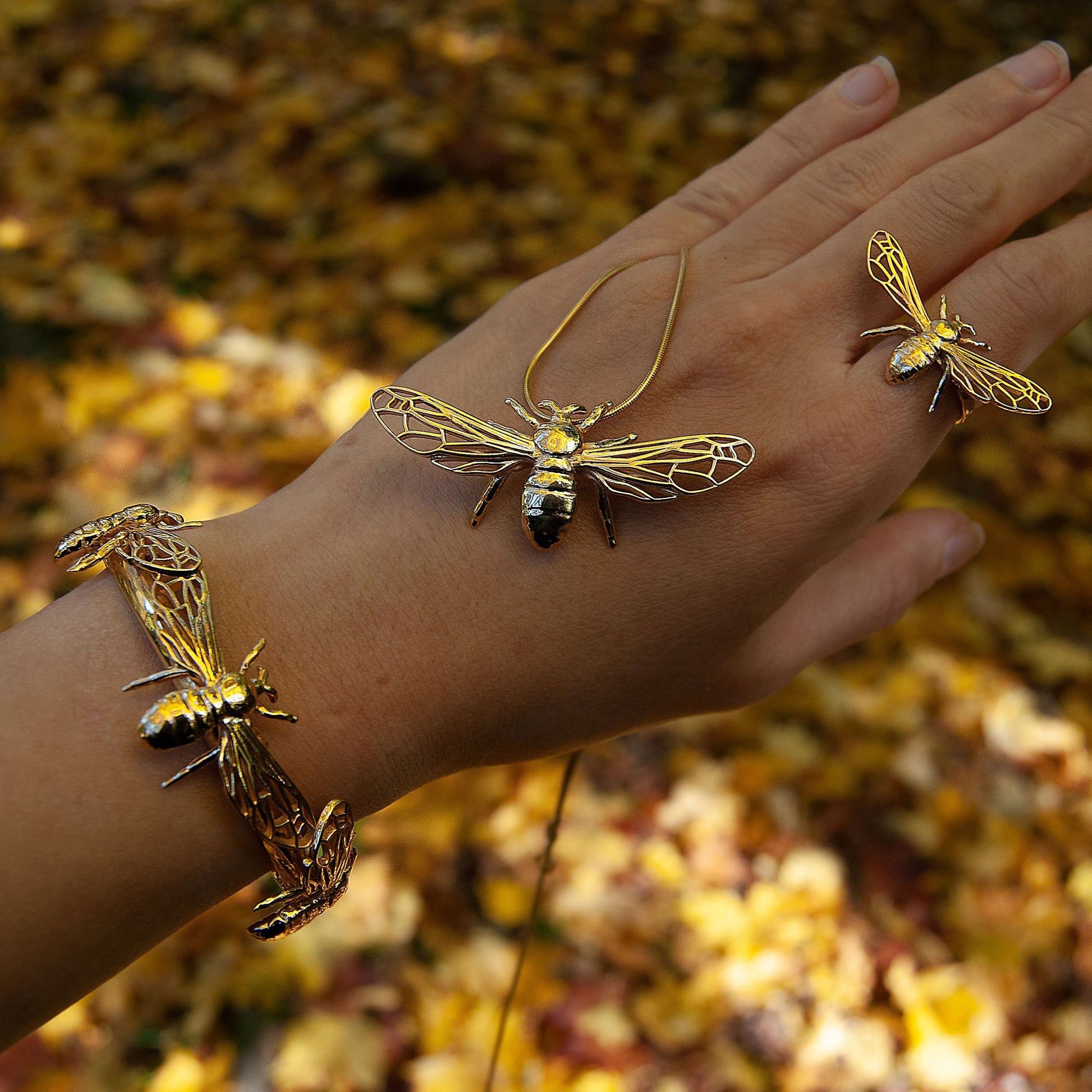 Bee pendant and matching rings worn on hand, top-down view