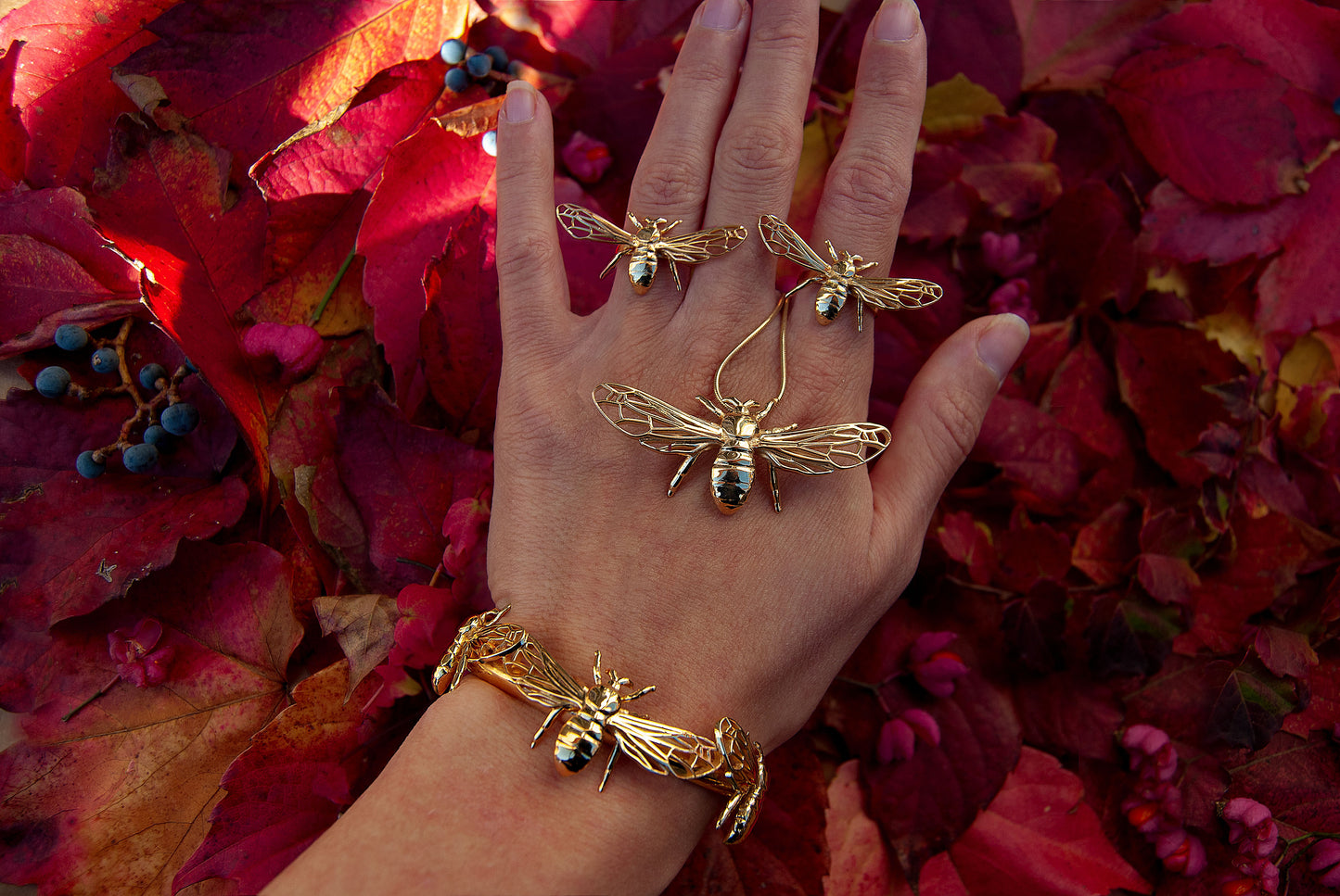 Model’s hand wearing gold bee bracelet, displaying detailed insect charm design.