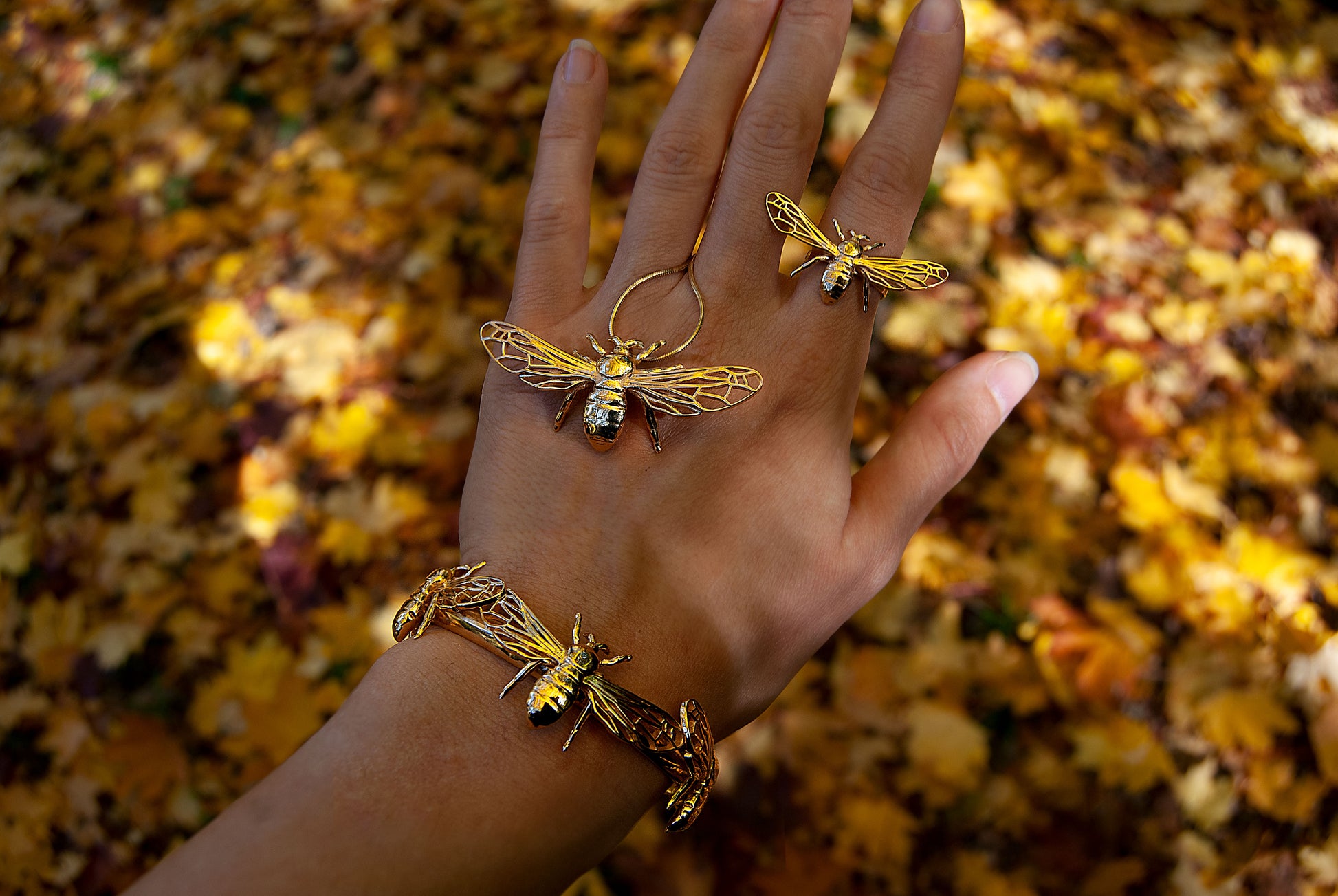 Close-up of bee pendant and rings styled on hand