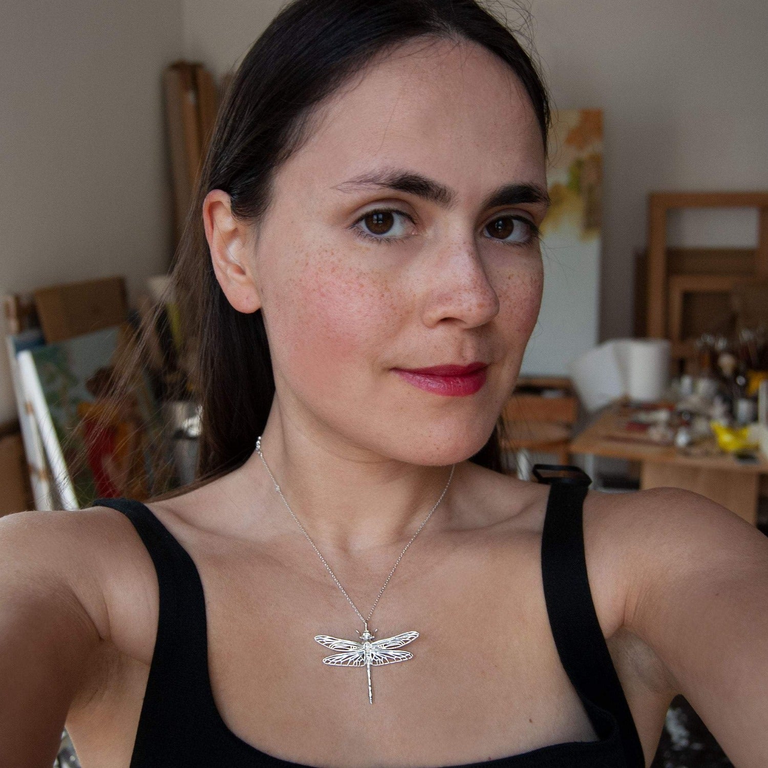 Model wearing handcrafted dragonfly pendant necklace, symbolic accessory and nature-inspired jewelry.