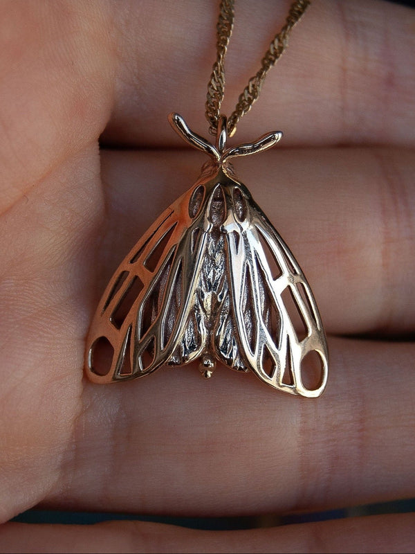 Alternative moth pendant in gold resting on hand, revealing winged insect jewelry design.